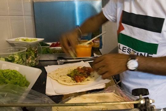 Refugiado prepara sanduíche no Al Janiah (Reprodução)